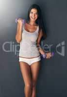 Fit body, playful and healthy woman exercising and feeling happy or confident with a workout. Fitness, exercise and health while lifting dumbbell weights and winking against a grey studio background