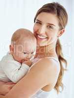 Mother bonding with baby boy, smiling and enjoying family time in a room at home. Portrait of a happy, loving and caring single parent holding or carrying an adorable, cute and little newborn child