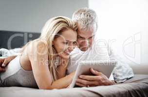 Well find fun activities for the weekend online. a mature couple using a digital tablet while lying in bed.