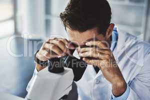 You have to look closely to see the bigger picture. a scientist using a microscope in a lab.