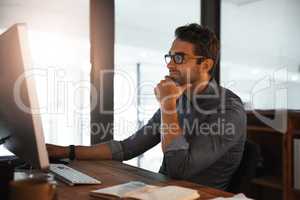 He shows dedication throughout the day and night. a young businessman working late on a computer in an office.