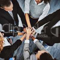The only way forward is together. High angle shot of a group of businesspeople joining their hands together in a huddle.
