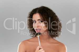 The perfect applicator for the perfect application. Studio shot of a beautiful young woman using a make up brush against a gray background.