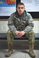 Reporting for duty. a young soldier sitting on a bench in the hall of a military academy.