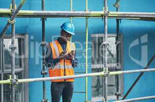 Male construction worker working checking a digital building plan on a phone. Busy urban development builder looking at buildings planning data to give industry information on a two way radio