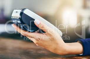 Electronic is the way forward in paying. Closeup of an unrecognizable person holding a card machine while standing inside of a cafe during the day.