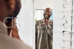 Customer trying on glasses at an optometrist, smiling and looking confident with choice at optical store . Carefree man buying trendy spectacles to help with vision. Excited male satisfied with frame