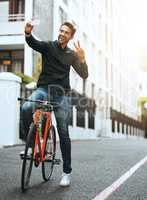 Peace out. Full length shot of a handsome young man taking selfies while traveling through the city by bike.