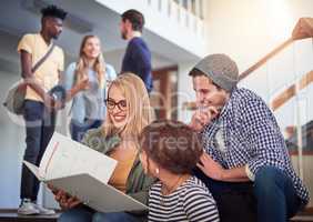 Its always helpful to have your study buddies. a group of university students working together on the staircase at campus.