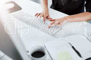 Flying across the keyboard at lightening speed. a businesswoman using a computer at her desk in a modern office.