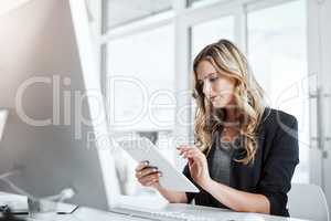 Tapped into a productive day at work. a young businesswoman using a digital tablet at her desk in a modern office.