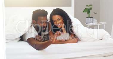 Capturing every moment to make the moment last. a young attractive couple taking a selfie in bed at home.