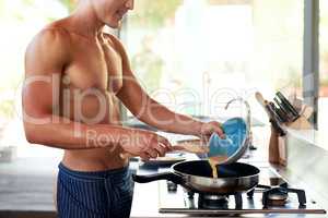 These are going to be some yummy eggs. an unrecognizable shirtless man making breakfast in the kitchen at home.