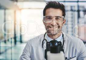 Science is about discovering new ways for a better life. Portrait of a young handsome male scientist working in a lab with a microscope.