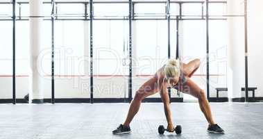 Get strong, you owe it to yourself. a young woman working out with weights in a gym.