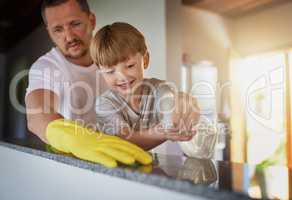 Involve your kids in becoming important contributors to the family. a father and his little son doing chores together at home.