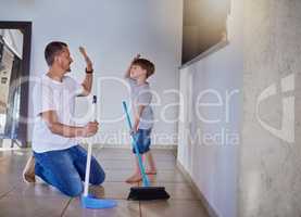 Good job buddy. a father and his little son high fiving each other while sweeping the floor at home.