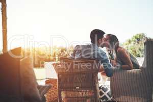 For your lips only. Rearview shot of an affectionate young couple kissing while enjoying some beers on their patio.