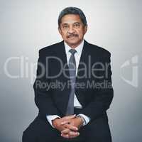 Hes experienced in his field. Studio portrait of a mature businessman posing against a grey background.