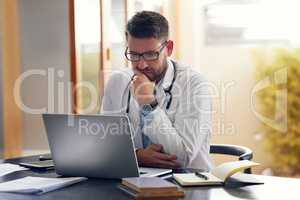 Medical records are the key to good health. a handsome male doctor working on his laptop while sitting in his office.