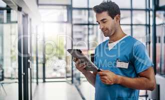 Updating his patients progress on his device. a young handsome male medical practitioner working in a hospital.