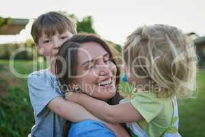 Mommy loves you loads too. a mother bonding with her two little children outdoors.