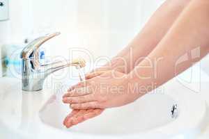 Every drop counts. Closeup shot of an unrecognizable woman washing her hands in the basin in the bathroom at home.