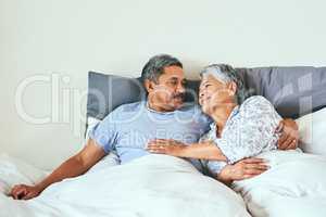 I have you and you have me. a relaxed mature couple lying in bed together at home in during the morning hours.
