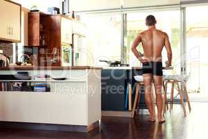 Before I begin breakfast I like to contemplate drinking coffee. Rearview shot of an unrecognizable shirtless man having a cup of coffee in the kitchen at home.