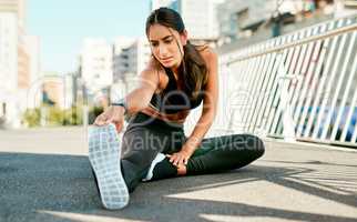 Progress only comes with persistence. a sporty young woman stretching before her run in the city.