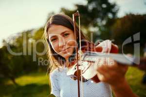 She found her passion at a young age. a young girl playing a violin outdoors.