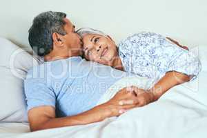 Lets do absolutely nothing today. a relaxed mature couple lying in bed together at home in during the morning hours.