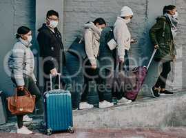 Traveling people wearing covid face mask and suitcases waiting in line or queue at the airport departure or arrival during a global coronavirus pandemic. Immigration of foreign tourists in quarantine