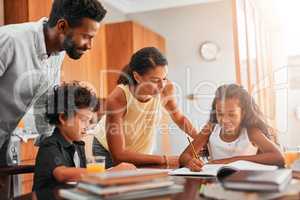 Getting homework done before playtime. parents helping their two children with their homework.