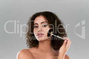 I can add blush in a rush with this applicator. Studio shot of a beautiful young woman using a make up brush against a gray background.