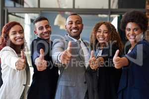 Keep positivity on your side. Portrait of a group of businesspeople showing thumbs up together in an office.