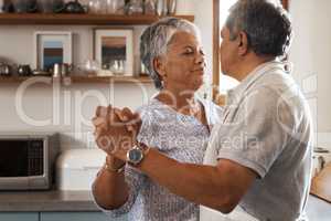 Are you ready to rock this retirement. a happy mature couple dancing together while cooking in the kitchen at home.