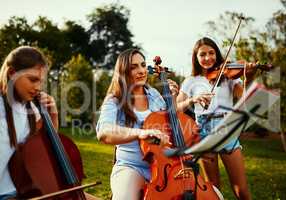 Being a band is great, being a family is better. a beautiful mother playing instruments with her adorable daughters outdoors.