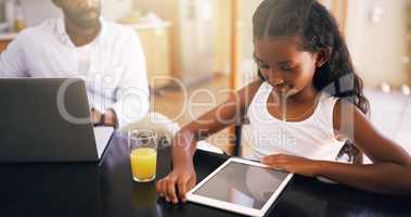 Getting educated digitally. a young father and his adorable daughter using a tablet at home.