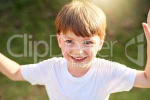 Sunshiny smiles on a sunshiny day. Portrait of an adorable little boy playing outside.