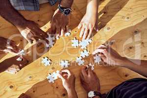Synergy forms the solutions we need. Closeup shot of an unrecognizable group of people completing a puzzle together.