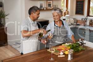 Retirement - no work, no worries. a happy mature couple drinking wine while cooking a meal together at home.