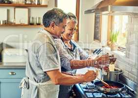 Seasoning turns good food into great food. a happy mature couple cooking a meal together at home.
