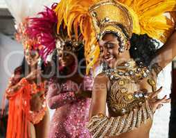 Theyre in the groove. three beautiful samba dancers performing in a carnival with their band.