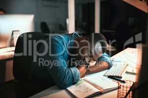 Totally exhausted. High angle shot of a young male designer sleeping at his desk while working late in the office.