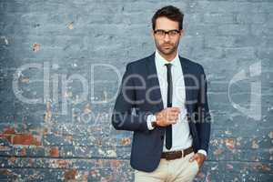 I always dress to impress. Cropped portrait of a handsome young businessman standing against a grey facebrick wall.