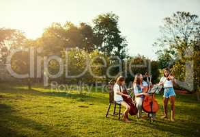 Her favourite part of the week, practicing with her girls. a beautiful mother playing instruments with her adorable daughters outdoors.