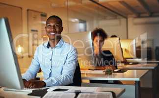 Success is dependent on your efforts. Portrait of a young businessman working late on a computer in an office.