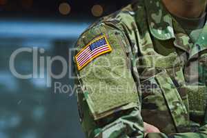 It takes someone special to serve their country. a soldier wearing camouflage fatigues with an american flag for a patch.