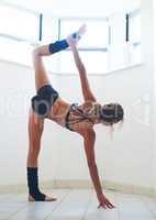 Flexibility is the key to moving forward. Full length shot of an attractive young female athlete working out at home.